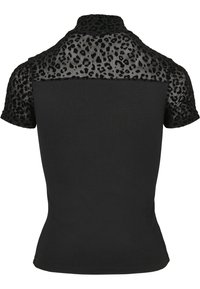 Svart kortermet topp med ensfarget svart kropp, og en gjennomsiktig panell med leopardmønster på øvre bak og ermer. Høy kragedesign.