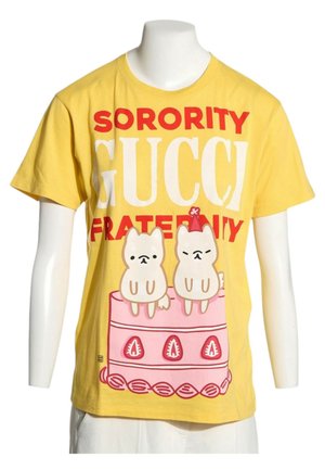 T-shirt jaune avec le texte "Sorority Gucci Fraternity" et une illustration de deux petits chiens assis sur un gâteau rose avec des décorations à la fraise.