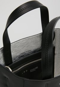 Black leather handbag featuring a sleek design, silver interior lining, and a zippered pocket with "Made in Italy" label.