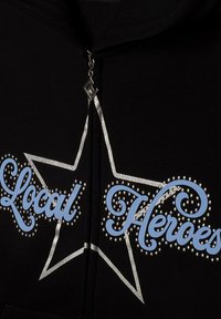 Czarna bluza z kapturem na zamek z napisem "Local Heroes" w niebieskim, stylizowanym kroju, obramowanym srebrem i ozdobionym dżetami, z graficznym wzorem gwiazdy.