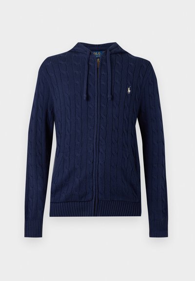 Μπλε ναυτικό φούτερ με φερμουάρ και πλέξη καλώδιο, μπροστινές τσέπες, κουκούλα με κορδόνι, ριμπ μανσέτες και μικρό λευκό κεντημένο λογότυπο στο στήθος.