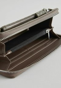 Brun læder wallet med lynlåslukning, der har flere kortpladser, et lynlåset rum og kontrasterende hvid syning. Teksturering på ydersiden.