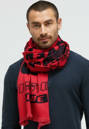 Red scarf with black text and graphic designs, made of soft material, featuring frayed edges. Worn layered around the neck.