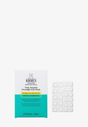 Boîte de Kiehl's Truly Targeted Overnight Acne Patch avec un design turquoise et blanc à côté d’une feuille transparente d’autocollants ronds anti-acné.