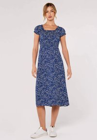 Blå blommig midiklänning med korta puffärmar, smockad byst och en luftig silhuett. Kombinerad med vita sneakers.