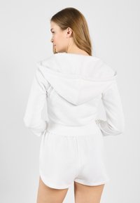 Hoodie blanc avec un cordon de serrage, des poignets côtelés et une coupe décontractée. Associé à un short blanc assorti, avec une taille élastique.