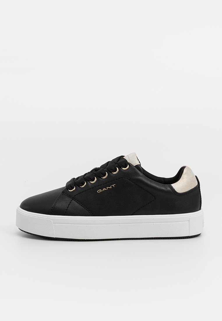 Sneaker in pelle nera con occhielli dorati, suola bianca e un accento di colore chiaro sul tallone. Presenta un logo sul lato.