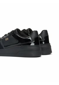 Zapatillas de charol negro con perfil bajo, punta redonda, cordones texturizados en negro y sutiles acentos en dorado en los laterales.