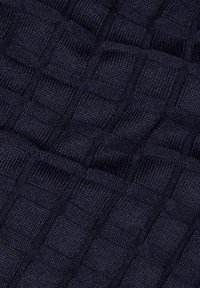 Mörkblått stickat tyg med ett strukturerat mönster som har upphöjda rutor. Materialet verkar mjukt och elastiskt, lämpligt för kläder.