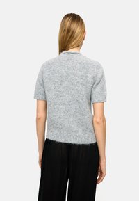 Szary sweter z krótkim rękawem o fakturowanej powierzchni z wielokolorowymi drobinkami, ze ściągaczem dopasowanym w talii. Tylny widok prezentuje okrągły dekolt.