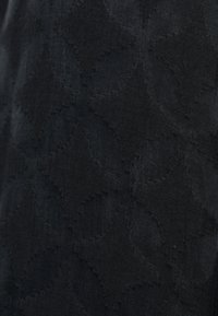 Texturovaná černá tkanina s jemným vzorem vzájemně propojených tvarů, vyrobená z hladkého syntetického materiálu.