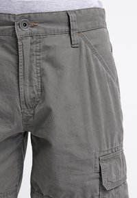 Bermuda grigie in tessuto leggero con chiusura a bottone, tasche anteriori oblique e tasca laterale a toppa. Tessuto dalla trama liscia.