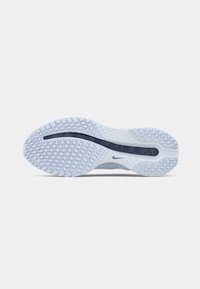 Nike sportcipő talpa, amelyen egy textúrázott fehér gumi felület található kék díszcsíkkal és egy kis logóval. Lekerekített, ergonomikus kialakítás.