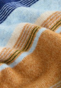 Gyapjú takaró váltakozó kék, krém, narancs és zöld csíkokkal. Puha tapintás, enyhén bolyhos felülettel.