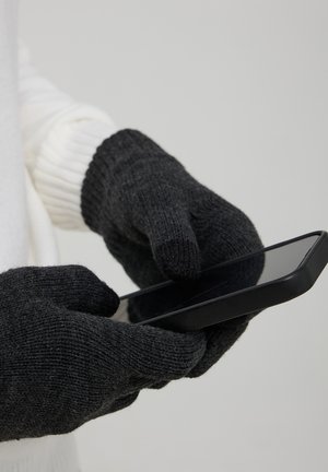 Guanti neri lavorati a maglia con tessuto texturizzato, forma aderente, accesso a pollice e dita, mentre si tiene uno smartphone. Manica bianca sottile visibile.