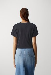 Kortärmad, svart bomullströja med en avslappnad passform, kombinerad med en högmidjad, ljusblå denimkjol med bakfickor.