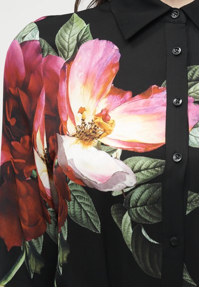 Camisa negra de botones con grandes estampados de flores rosas y rojas y hojas verdes en la parte delantera y el hombro.