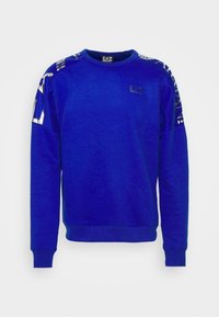 Sweat-shirt bleu à col rond, avec des accents métalliques sur les épaules et un petit logo sur la poitrine. Tissu doux et texturé.