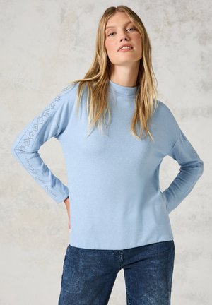 Lichtblauwe trui met lange mouwen, featuring een hoge hals en decoratieve stiksels langs de mouwen. Zachte textuur, ontspannen pasvorm.
