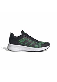 Chaussure de sport noire avec motifs pixellisés verts, dessus texturé et semelle intermédiaire blanche. Elle présente des lacets noirs et un logo vert sur le talon.