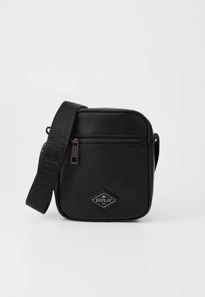 Black synthetic crossbody bag with a zip closure, square shape, adjustable strap, and a diamond logo patch on the front.