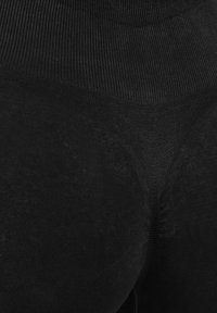 Schwarze Strumpfhosen mit gerippter Textur, hoher Taille und glatter Oberfläche. Der Stoff wirkt dehnbar und eng anliegend.