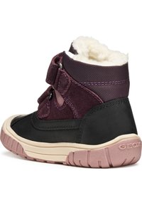 Botas infantiles negras y moradas con suave forro blanco, tiras de velcro, suela de goma y detalles texturizados. Marca Geox en la suela.