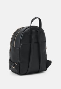 Zwarte leren rugzak met twee riemen, een bovenhandvat en gouden ritsdetails op een witte achtergrond.