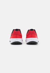 Zapatillas deportivas rojas con detalles en negro, parte superior de malla, cuello acolchado y suela blanca flexible con tracción texturizada en negro en la parte inferior.