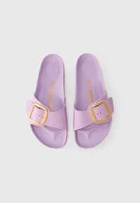Infradito lavanda con una larga fascia e una fibbia dorata, realizzate in materiale lisciocon una soletta imbottita.