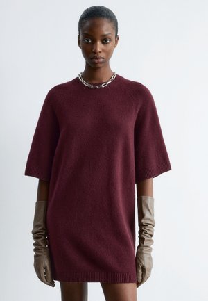 Burgundy knit dress with short sleeves, ribbed hem, and a crew neck. Paired with long, ruched brown leather gloves and a silver chain necklace.