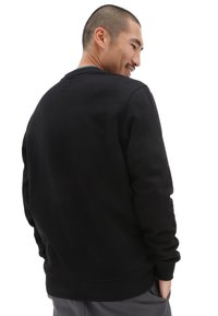 Czarny sweatshirt z okrągłym dekoltem i długimi rękawami. Gładka faktura, ściągacze przy mankietach i u dołu, pokazujący widok z tyłu z minimalnymi detalami.