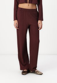 Maroon textured wide-leg pants with an elastic waistband, paired with leopard print flats. Smooth fabric with a subtle sheen.