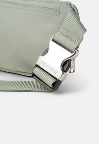 Borsa in nylon verde con una fibbia in metallo argentato. Presenta una tracolla testurizzata e dettagli cuciti all'esterno. Design compatto e funzionale.