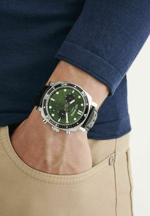 Green dial watch with silver stainless steel case, black leather strap, and chronograph functions; features a textured dial and luminescent markers.