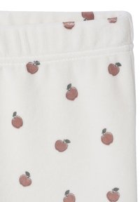 White fabric featuring a repeating pattern of small red apples with green leaves. Soft texture, elastic waistline detail.