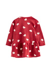 Red dress with long sleeves, white heart pattern, soft velvety texture, gathered waist, and flared skirt. Back view displays neckline and sleeves.