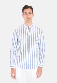 Camicia bianca a maniche lunghe con strisce verticali blu, chiusura con bottoni e colletto alla cinese. Realizzata in tessuto leggero.