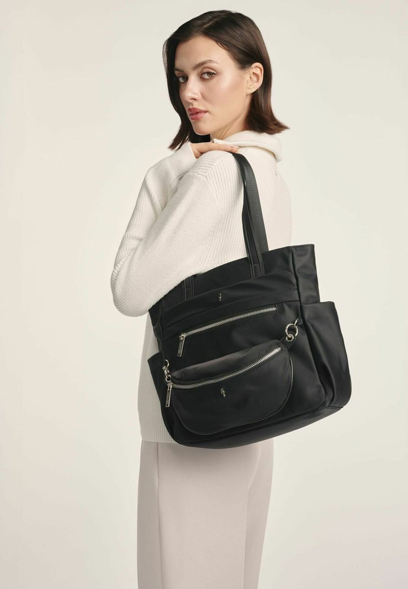 Czarna torba tote z nylonu z wieloma zamykanymi kieszeniami i teksturowanym wykończeniem, z podwójnymi uchwytami oraz zakrzywionym designem przedniej kieszeni.