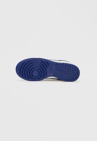 Podeszwa buta Nike, z niebieską gumową bieżnią o okrągłych i liniowych wzorach, teksturowana dla lepszej przyczepności, ozdobiona logo Nike.