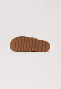 Brun såle med horisontale spor, flat design, gummimateriale, med en merkelapp med "CALLE STRETCH" preget på siden.