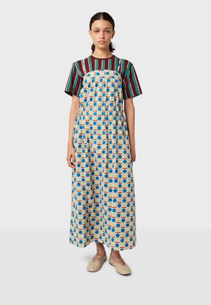 Vintage-tyylinen mekko vaaleanbeigellä pohjalla, jossa on suuria sinisiä ja oransseja pilkkuja. Mekossa on neliömäinen pääntie, säädettävät olkaimet ja sivutaskut.