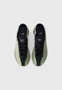 Roheline ja must perforatsiooniga disainiga tossud, paeltega kinnitamine ja ümar varvas. Tal on Nike logo keelel ja külgmisel osal.