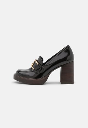 Mocassin à plateforme en cuir verni noir avec talon bloc en bois massif et détail de boucle dorée sur le cou-de-pied.