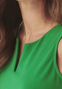 Green sleeveless top with a V-neckline, made from a smooth fabric. Features a clean design with a subtle, soft texture.