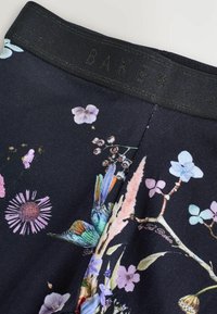 Tessuto nero con un motivo floreale che presenta fiori viola e blu, accenni di verde e un colibrì, con un cinturino scuro.