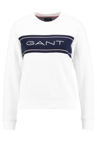 Witte trui met ronde hals, voorzien van een navy blauwe horizontale streep en het "GANT"-logo in wit. Geribbelde manchetten en zoom, zachte textuur.