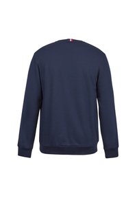 Sweat-shirt à manches longues bleu marine avec poignets et ourlet côtelés, vu de dos, présentant une petite étiquette en tissu tricolore au niveau de l'encolure.