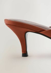 Offene Zehen Sandalette aus verbranntem Orange Stoff, mit geschwungener Silhouette und schlankem schwarzen Absatz. Glatte Textur mit minimalen Akzenten.