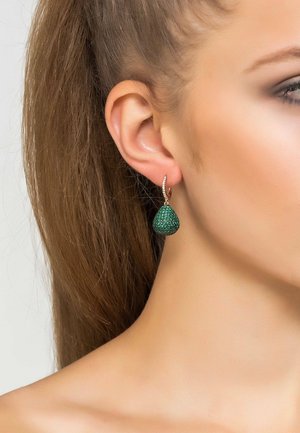 Orecchini a goccia verde scintillanti con forma a goccia, attaccati a un anello di argento texturizzato, indossati all'orecchio di un modello.